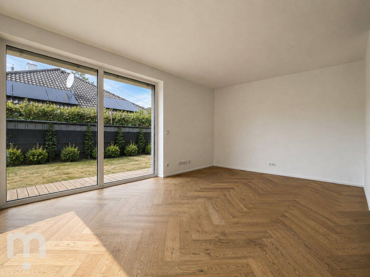Geräumiges Wohnzimmer mit hellem Fischgrätparkett und großen Fenstern zum Garten.