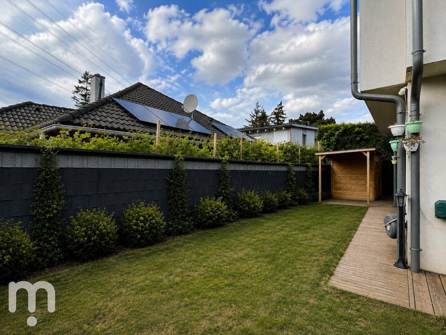 Gepflegter Gartenbereich mit Rasenfläche, Gartenhaus und Sichtschutz zum Nachbargrundstück.