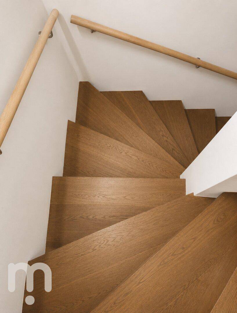 Elegante Holztreppe mit schlichtem Geländer, die die verschiedenen Etagen verbindet.