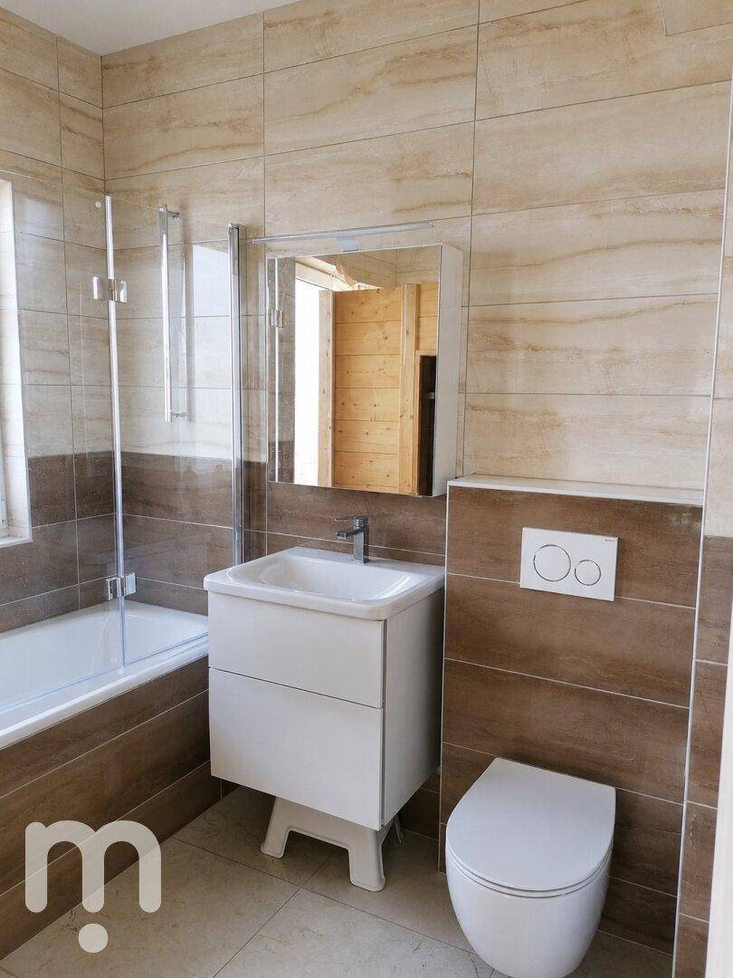 Modernes Badezimmer mit Badewanne, Waschtisch und Wand-WC in neutralen Farbtönen.