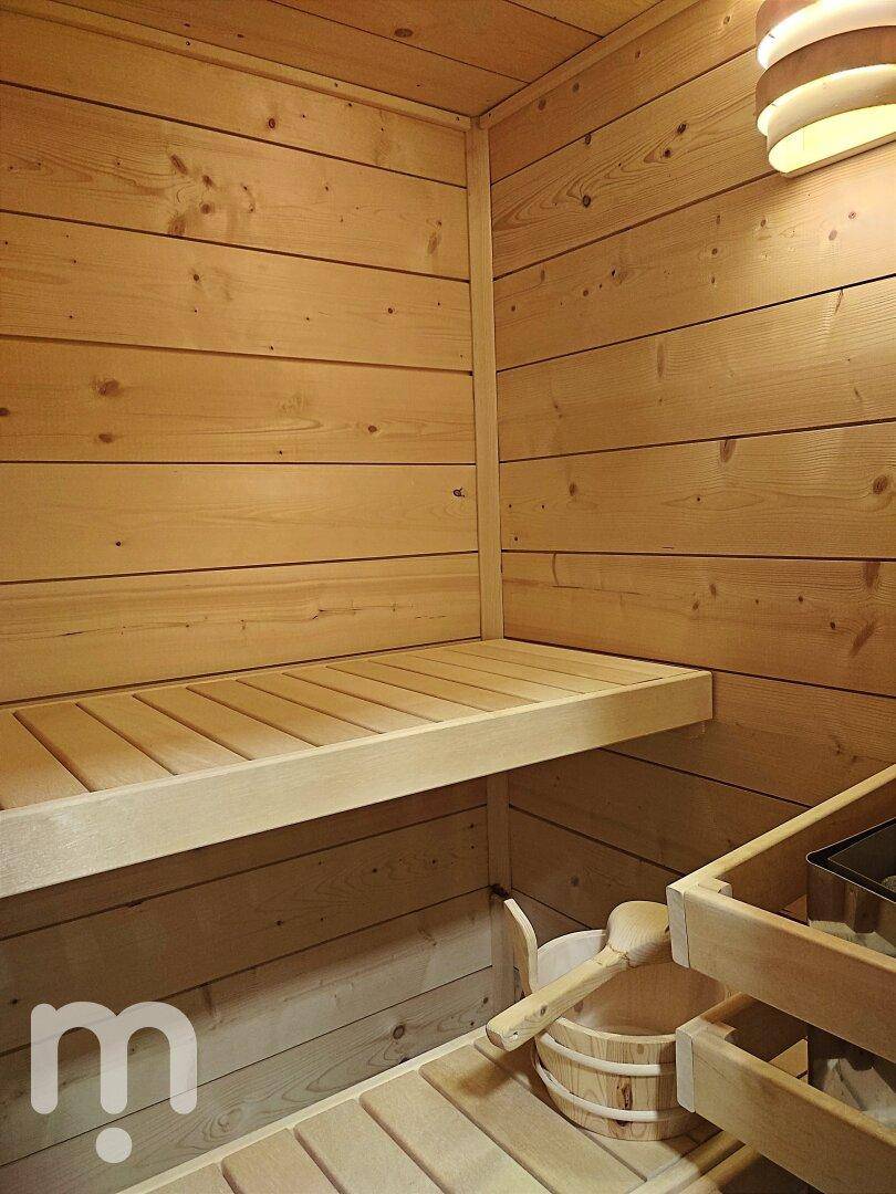 Gemütliche Holzsauna mit Sitzbänken und traditionellem Saunaofen für Wellnessmomente.