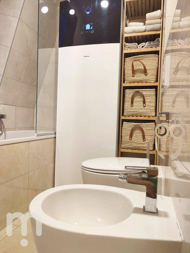 Modernes Badezimmer mit Bidet, WC und Wärmepumpe, hell und funktional gestaltet.
