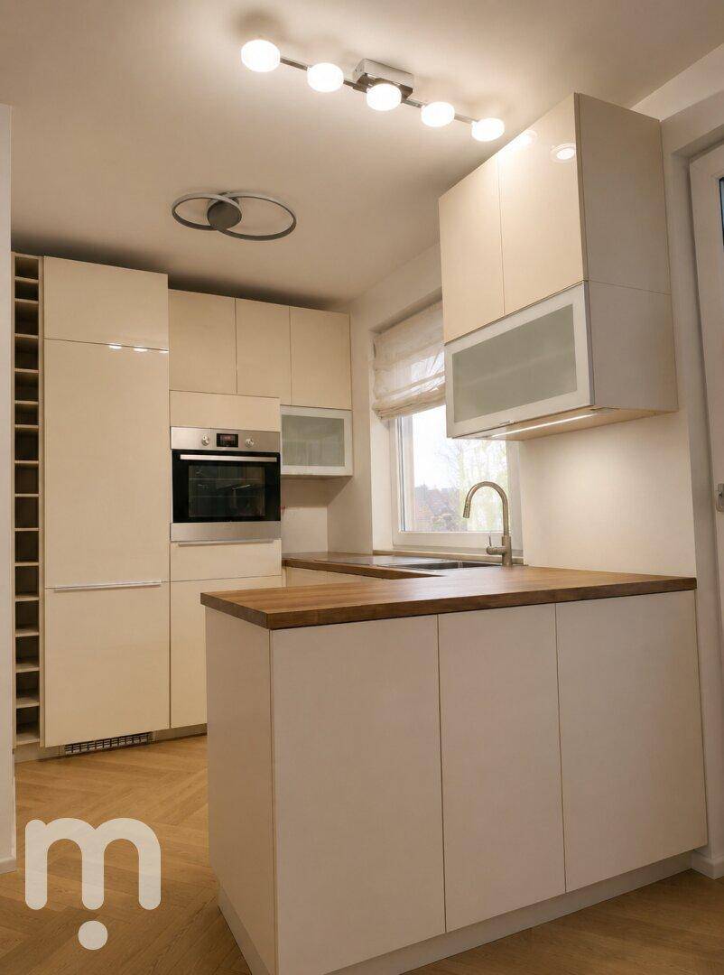 Moderne Einbauküche in hellem Design mit Holz-Arbeitsplatten und integrierten Geräten.