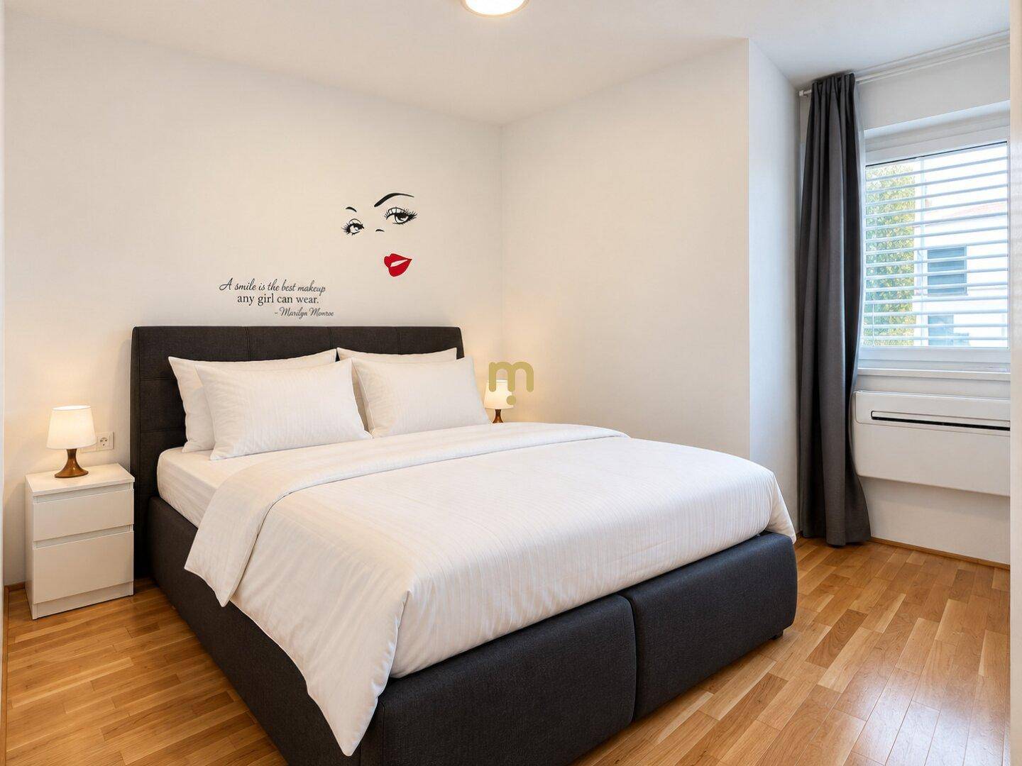 Gemütliches Schlafzimmer mit Doppelbett, Nachttischen und einem Fenster mit Jalousien.