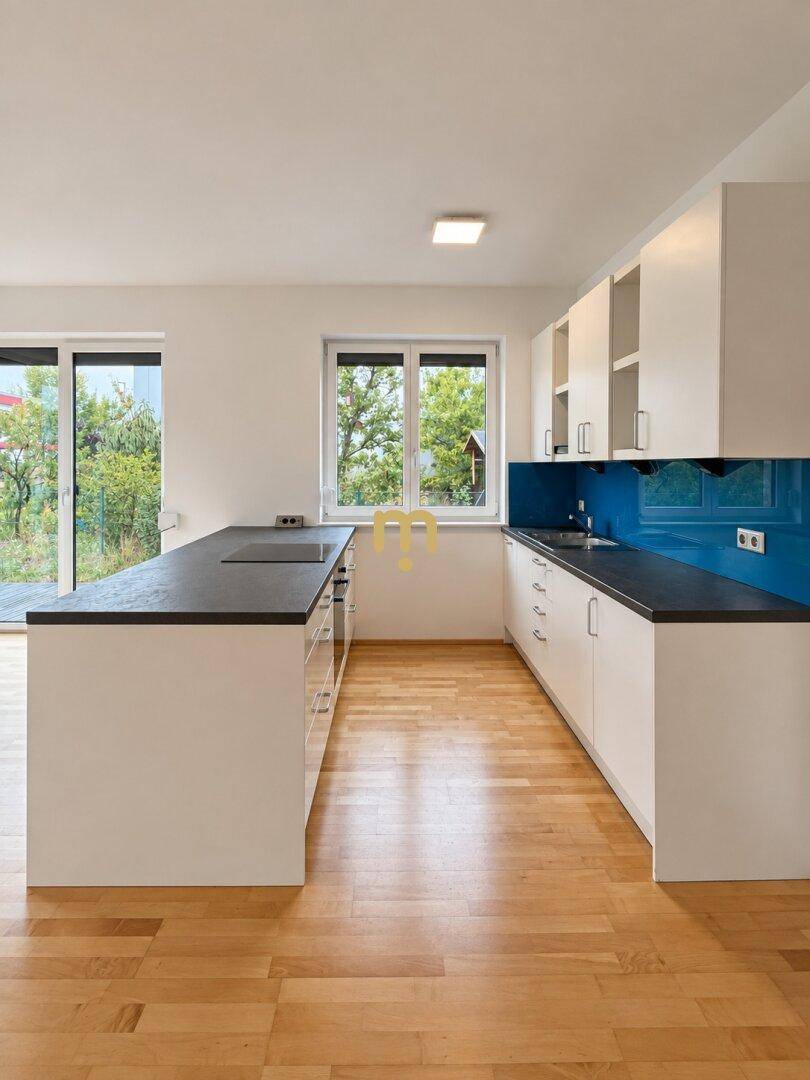 Helle Küche mit Kücheninsel, blauer Rückwand und Fenster zum Garten.