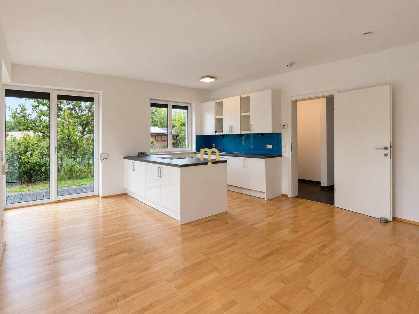 Offener Wohnbereich mit moderner Küche, Holzboden und Blick in den Garten.