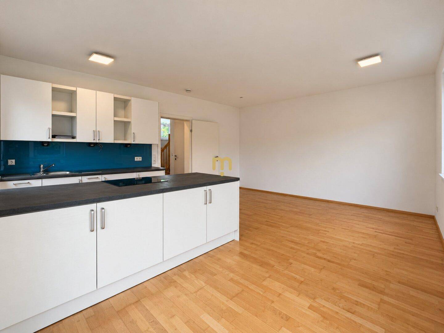 Moderne Einbauküche mit weißer Front, dunkler Arbeitsplatte und Holzboden.