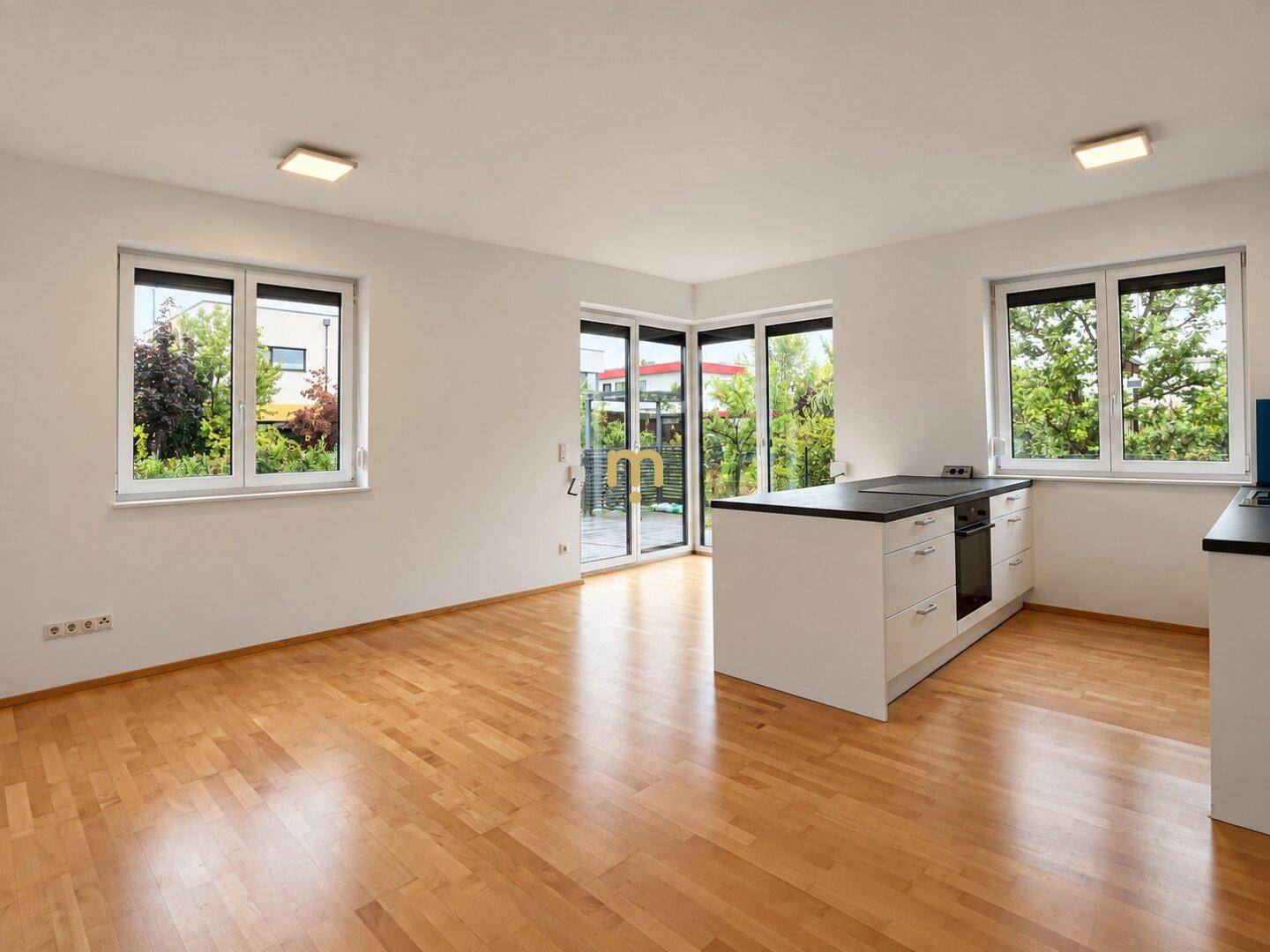 Heller offener Wohnbereich mit Holzboden, Kücheninsel und Zugang zur Terrasse.