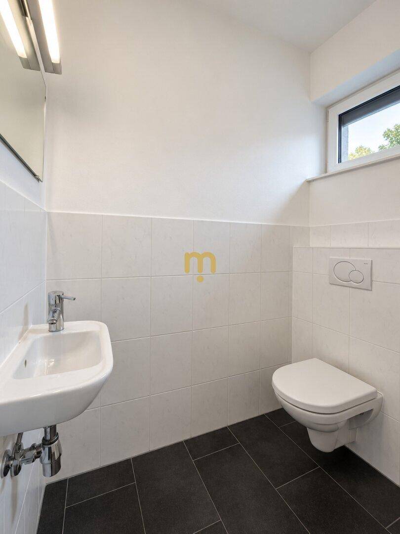 Modernes Gäste-WC mit wandhängendem WC, Waschbecken und Fenster.