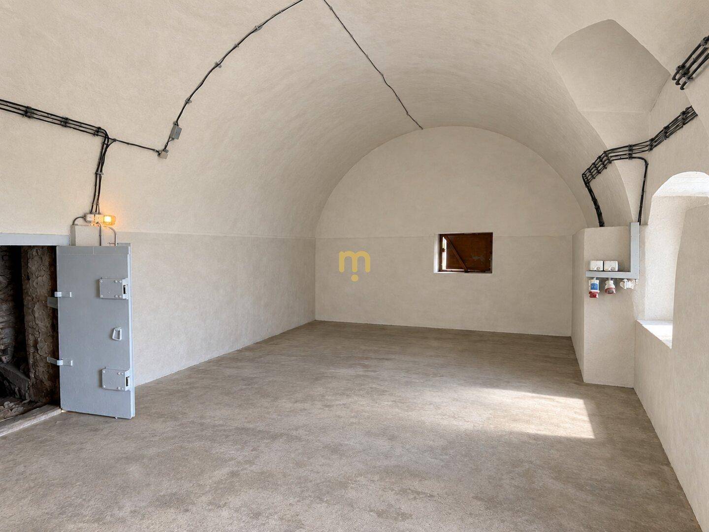 Gewölbter Kellerraum mit Betonboden und sichtbaren Elektroinstallationen, ideal als Lagerfläche.