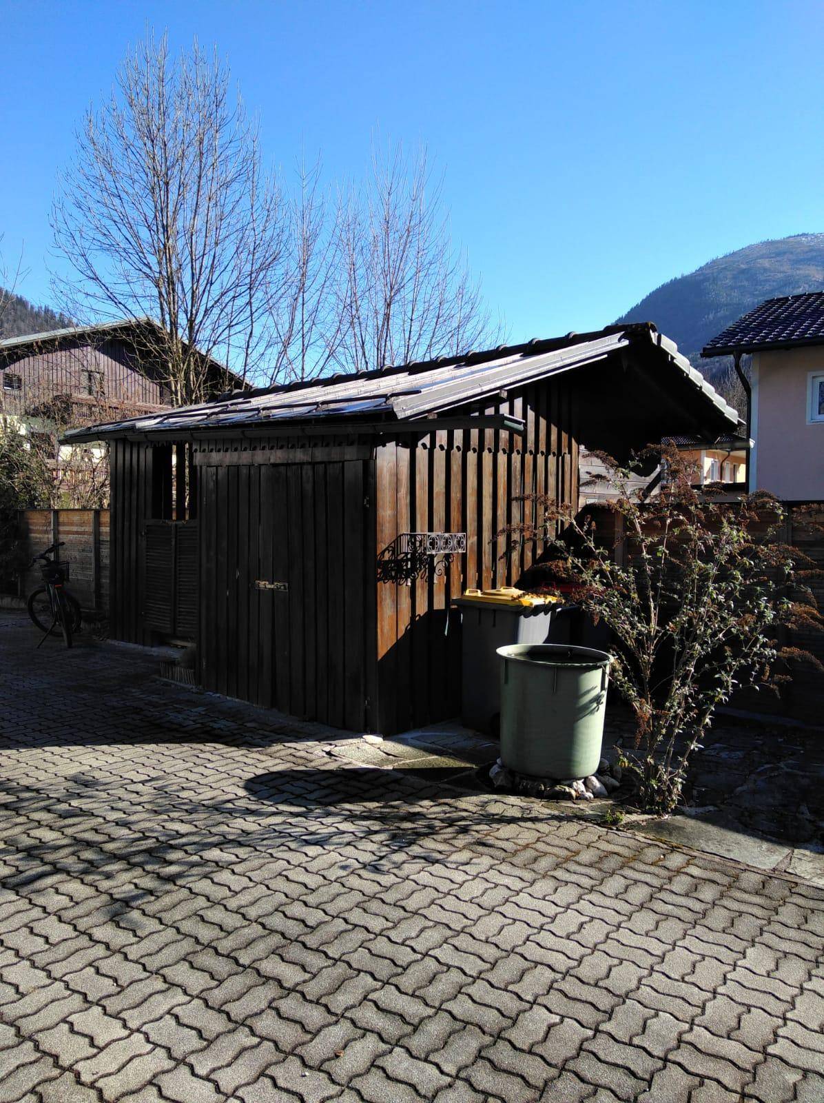 Rustikaler Holzschuppen mit Satteldach und gepflastertem Vorplatz im Außenbereich.