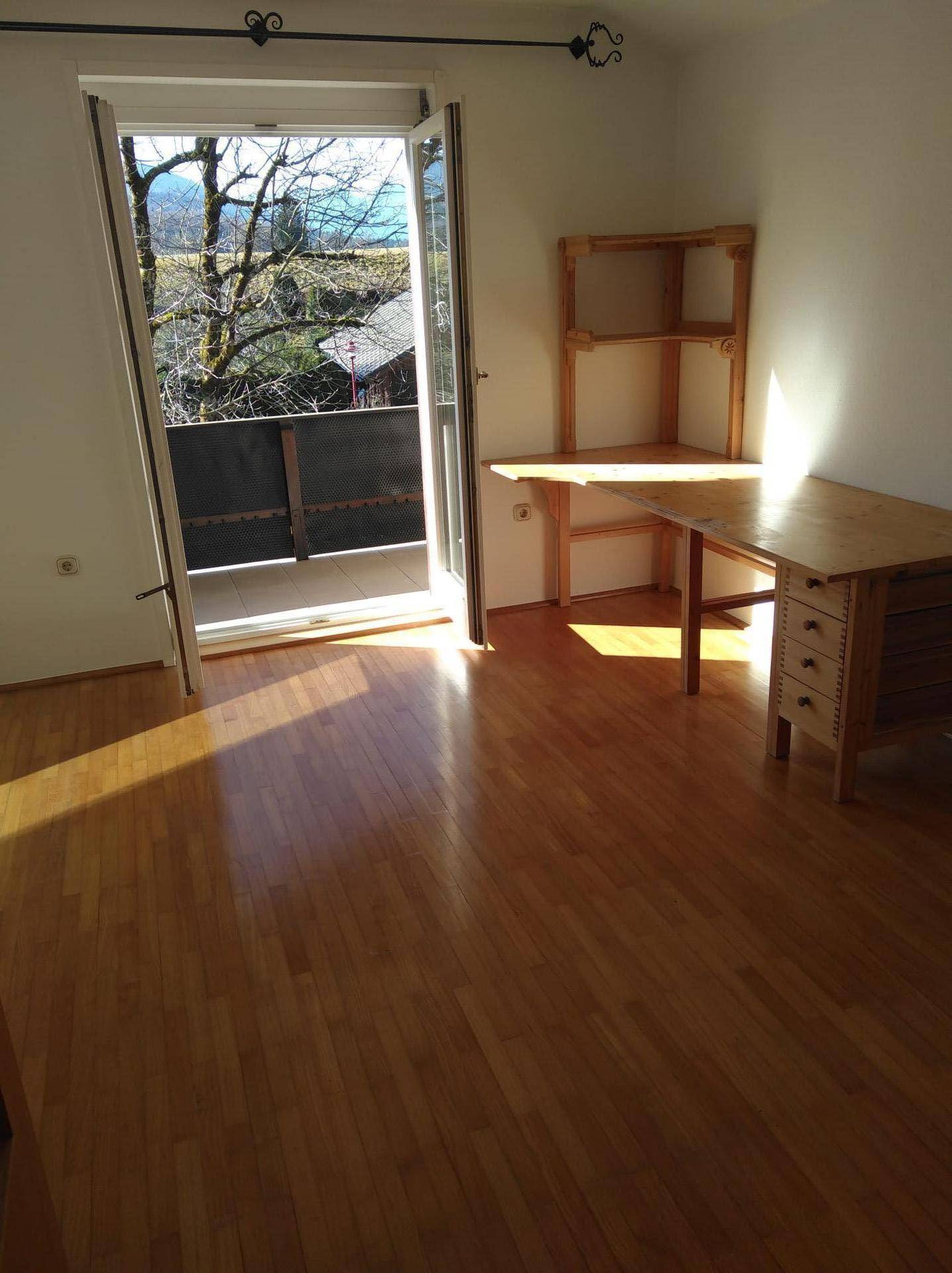 Helles Zimmer mit Holzboden, Balkonzugang und viel natürlichem Licht.