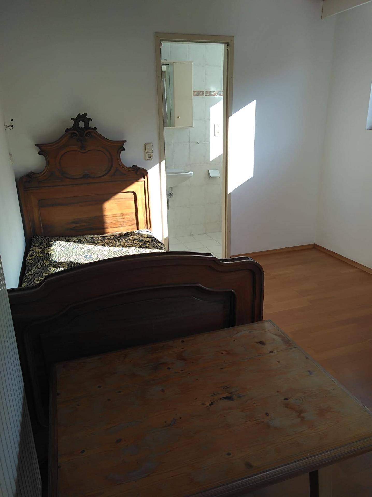 Schlafzimmer mit Holzbett und direktem Zugang zu einem eigenen Badezimmer.