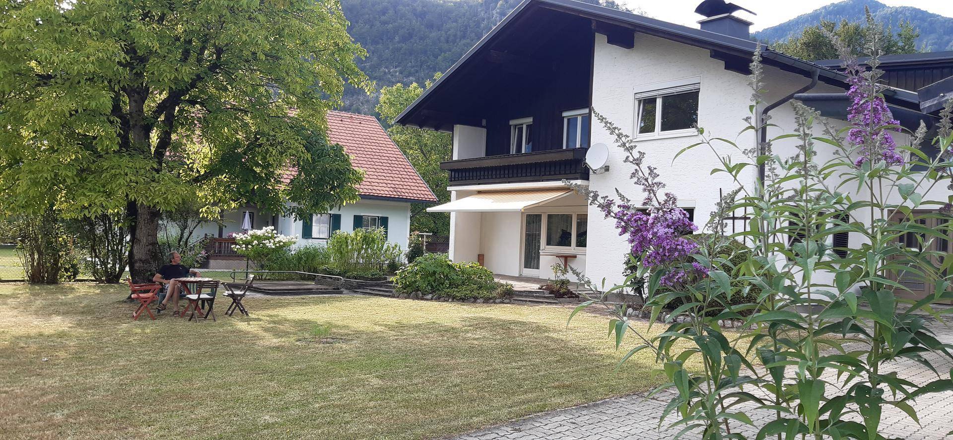 Ansicht des Hauses vom Garten aus mit einem weiteren Gebäude und Bergpanorama.