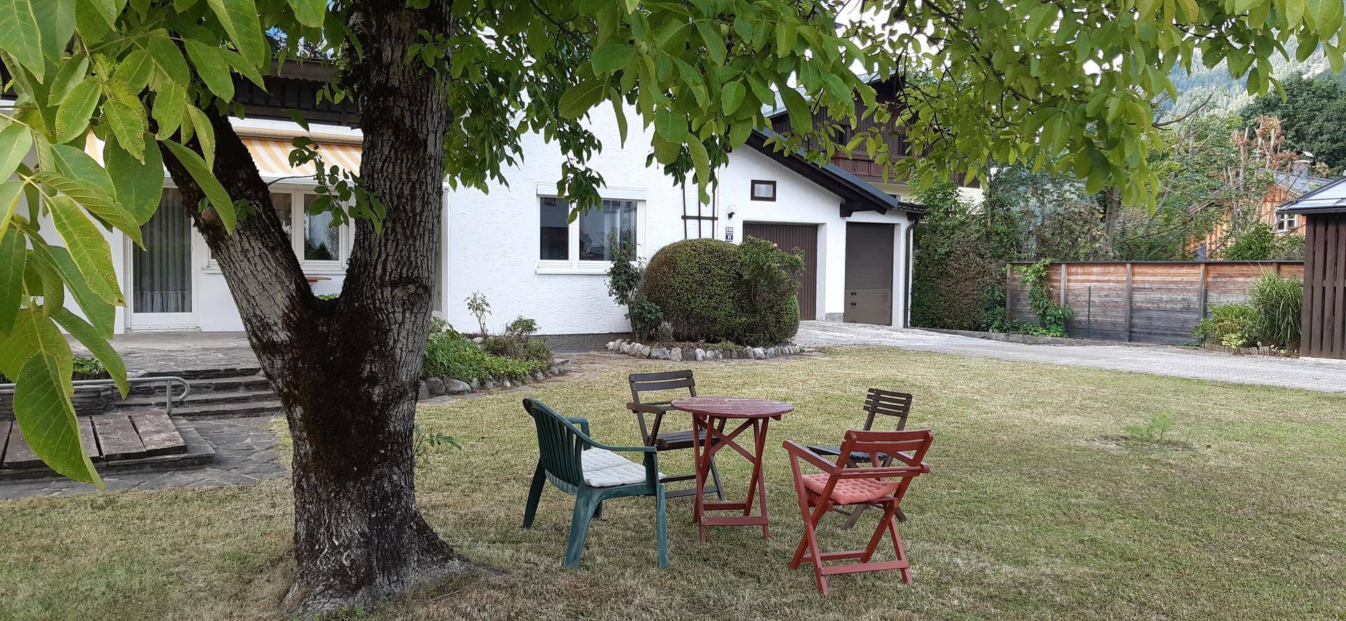 Gartenbereich mit Sitzgruppe unter einem Baum und Blick auf das Wohnhaus.