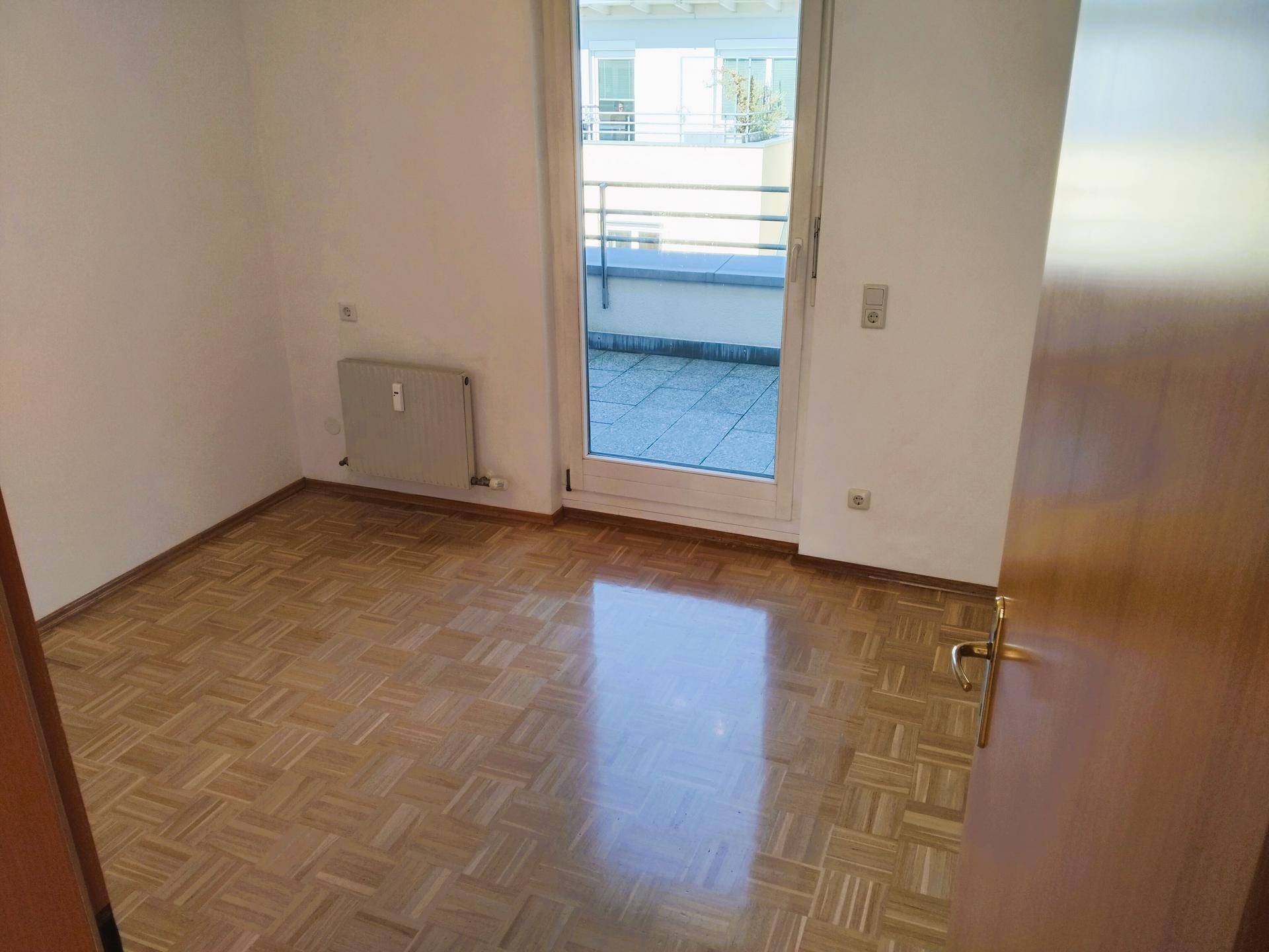Helles Schlafzimmer mit Parkettboden und direktem Zugang zu einer sonnigen Terrasse.