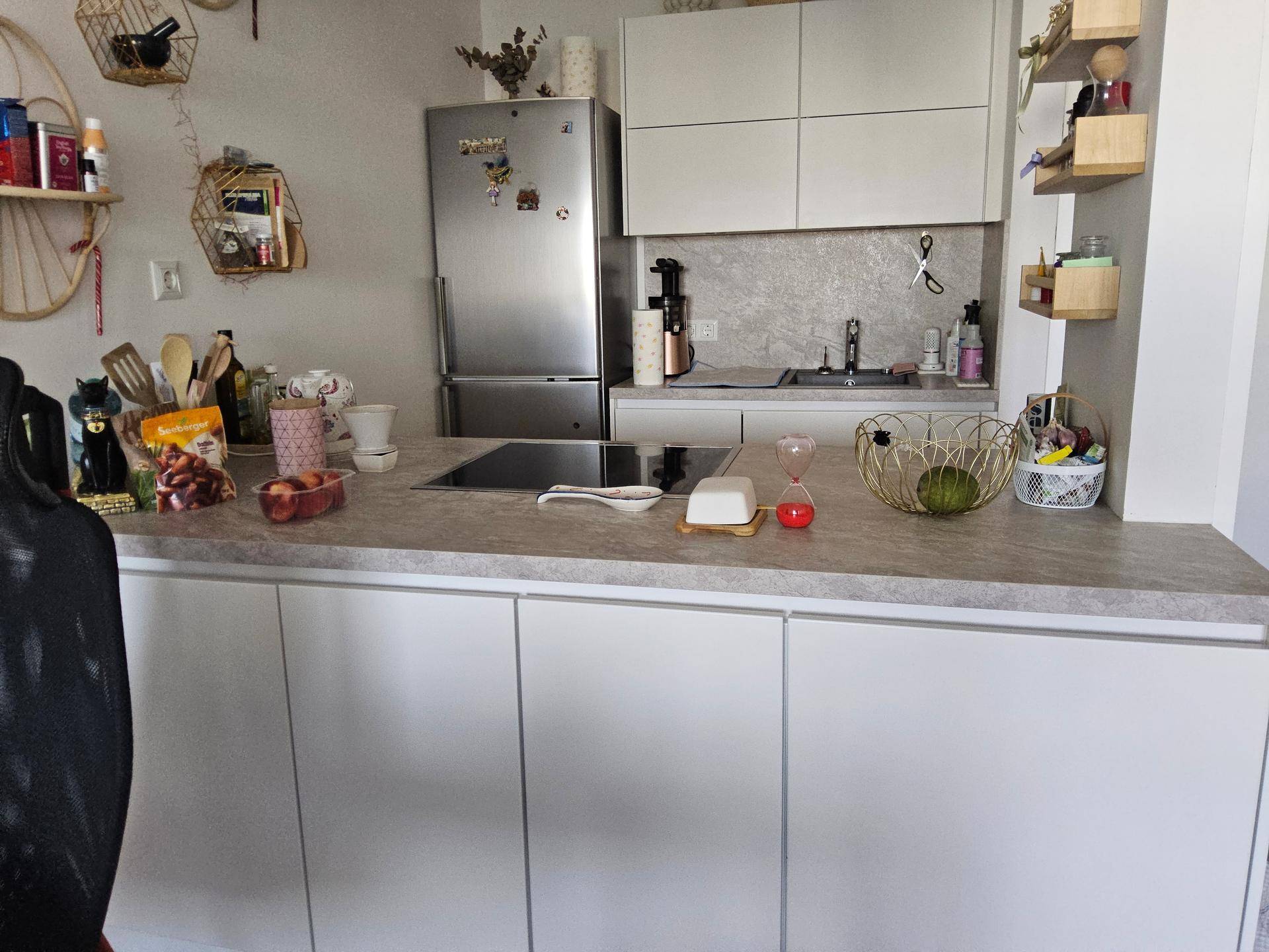 Helle Küche mit Kücheninsel, weißen Schränken, Kühlschrank und Induktionskochfeld.