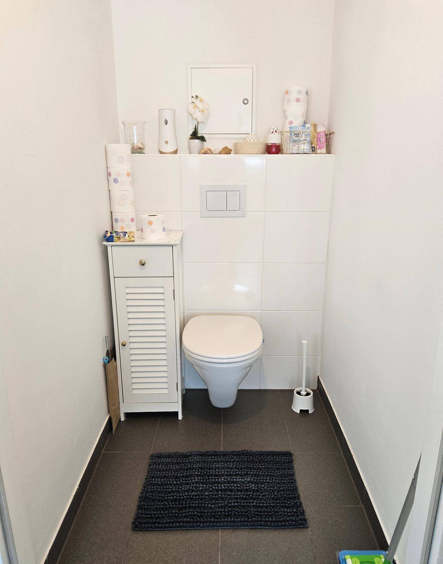 Kleines Gäste-WC mit wandhängender Toilette und praktischem Stauraum in hellem Design.