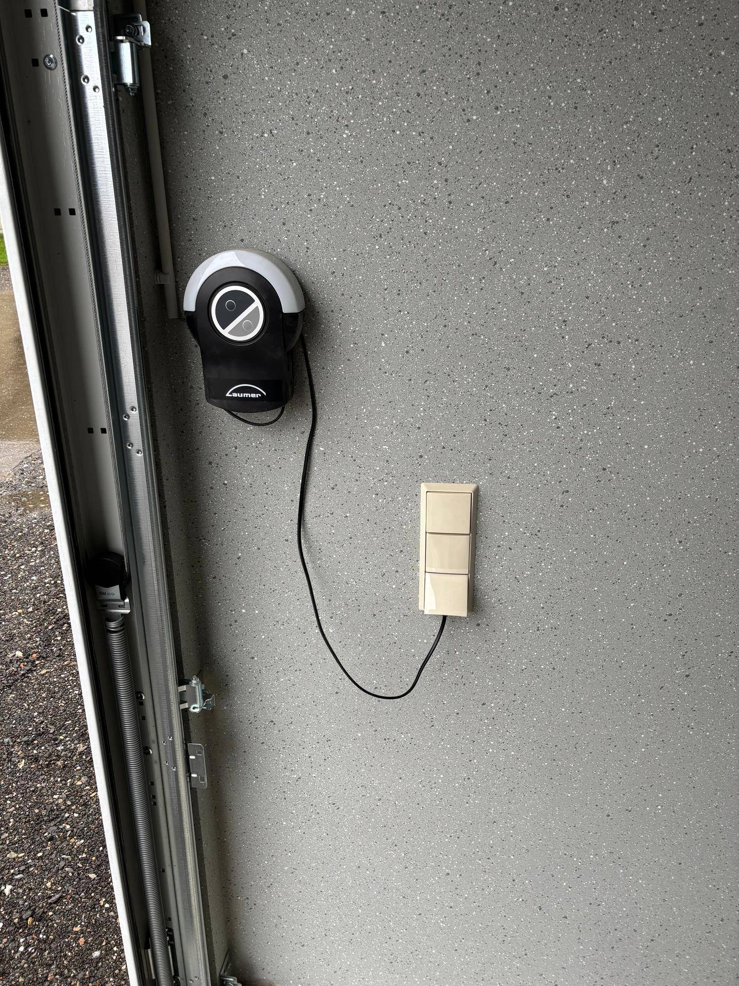 Garagentoröffner und Lichtschalter an einer gesprenkelten Wand im Inneren der Garage.