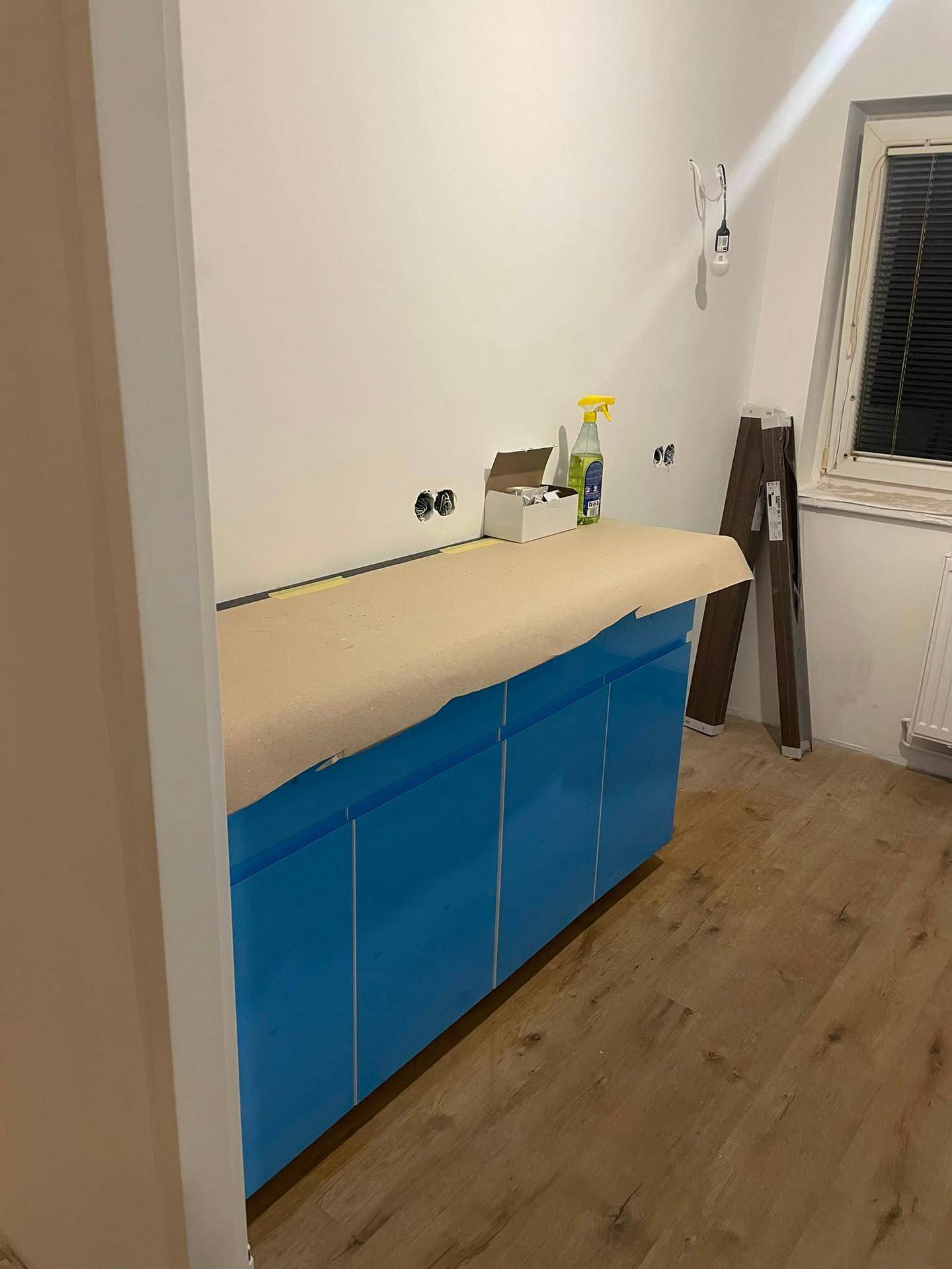 Unfertige Küche mit blauen Unterschränken und vorbereiteter Arbeitsfläche.