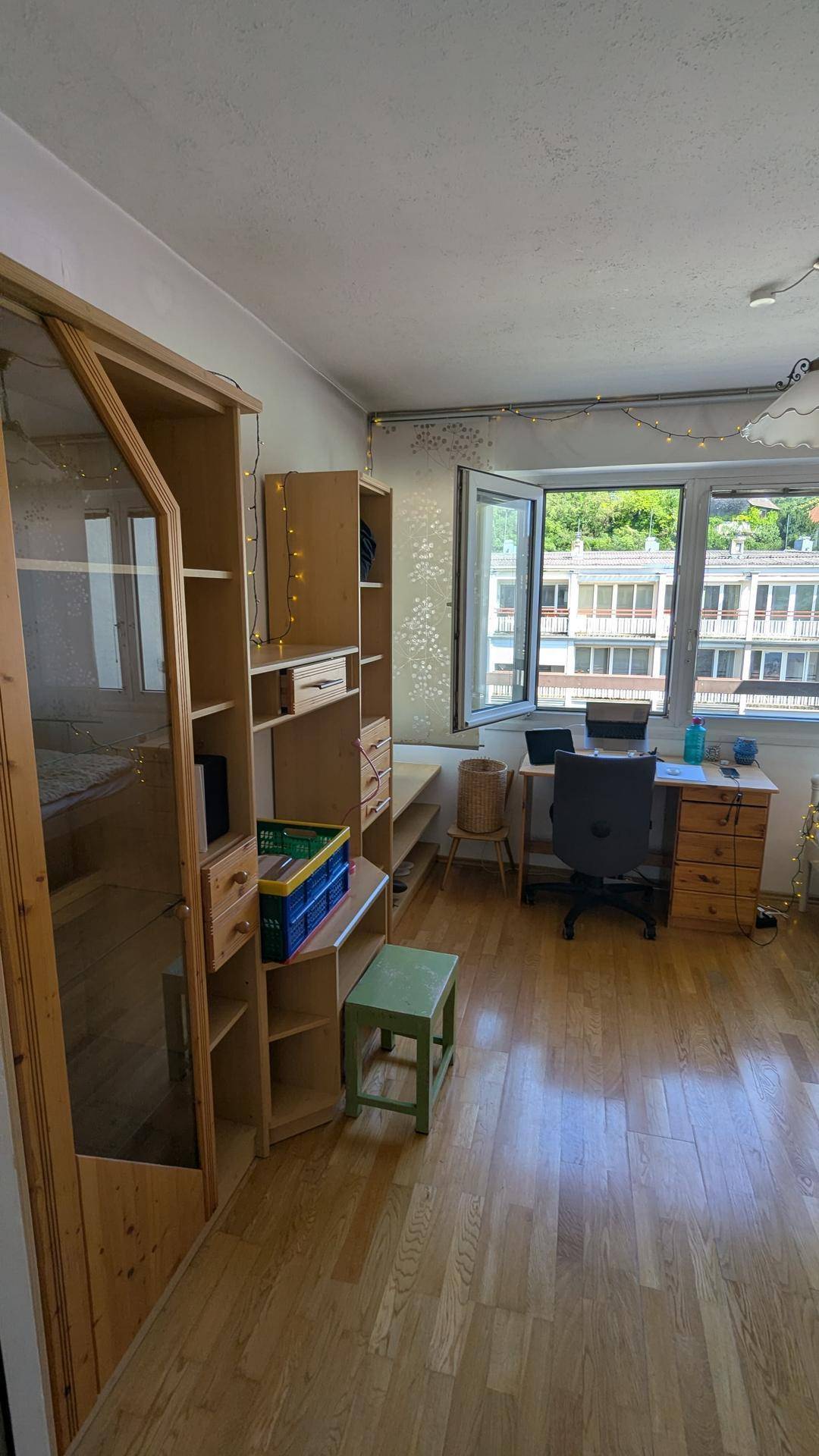 Kinderzimmer oder Arbeitszimmer mit Holzboden, Schreibtisch und großem Fenster mit Ausblick.