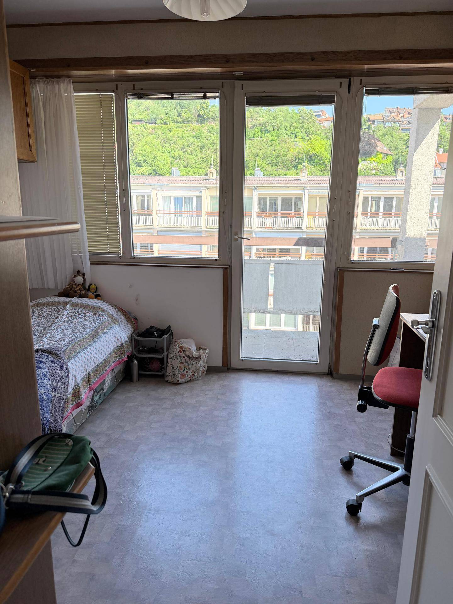 Helles Zimmer mit Bett, Schreibtisch und Balkonzugang, bietet einen schönen Blick ins Grüne.