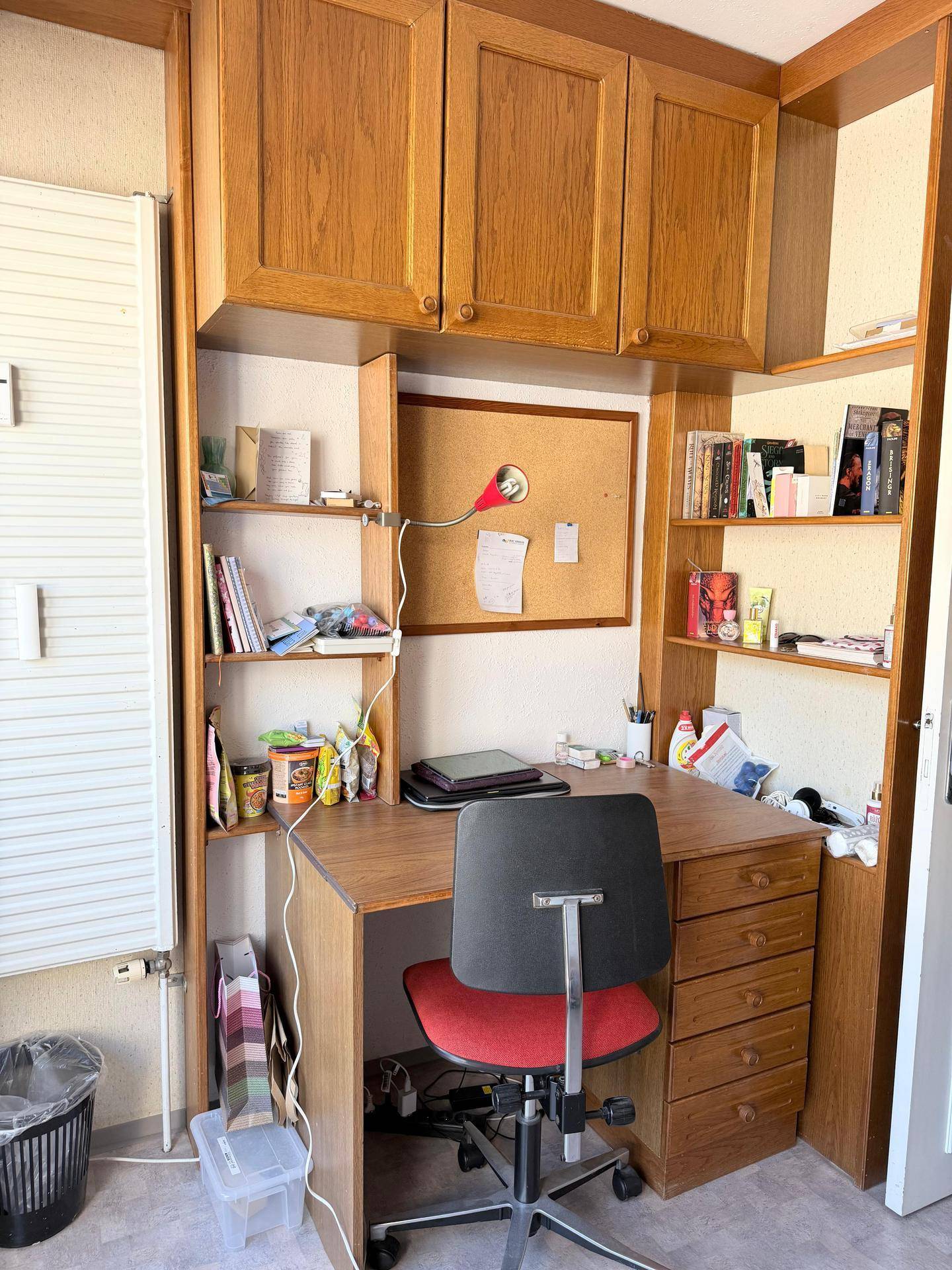 Funktionaler Arbeitsbereich mit Holzschreibtisch, integrierten Regalen und Pinnwand.