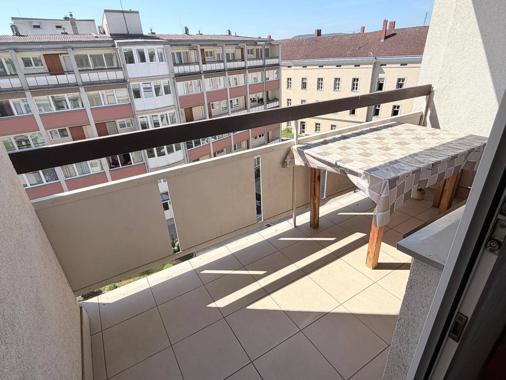 Sonniger Balkon mit Fliesenboden und kleinem Tisch, ideal für entspannte Stunden im Freien.