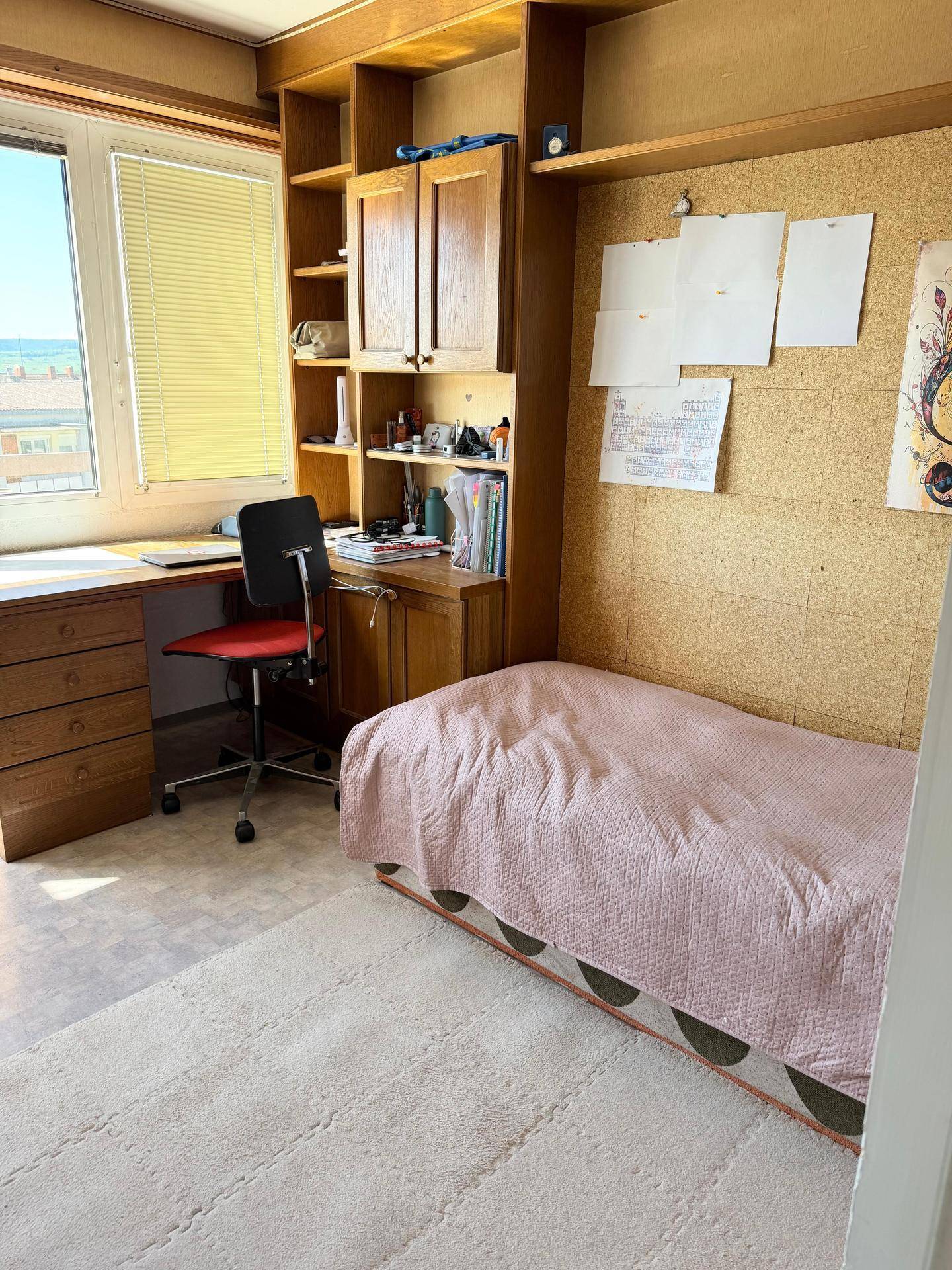 Helles Zimmer mit Einzelbett, Schreibtisch und Einbauregalen, ideal als Kinder- oder Arbeitszimmer.