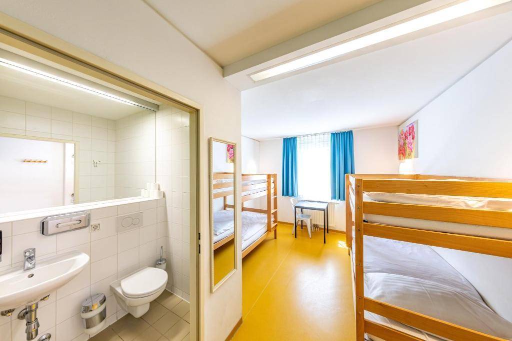 Geräumiges Schlafzimmer mit mehreren Etagenbetten und einem angrenzenden Badezimmerbereich.