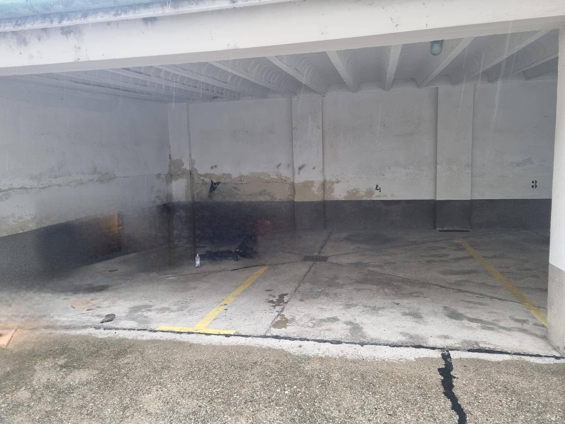 Zwei leere überdachte Garagenstellplätze mit Betonboden und sichtbaren Markierungen.