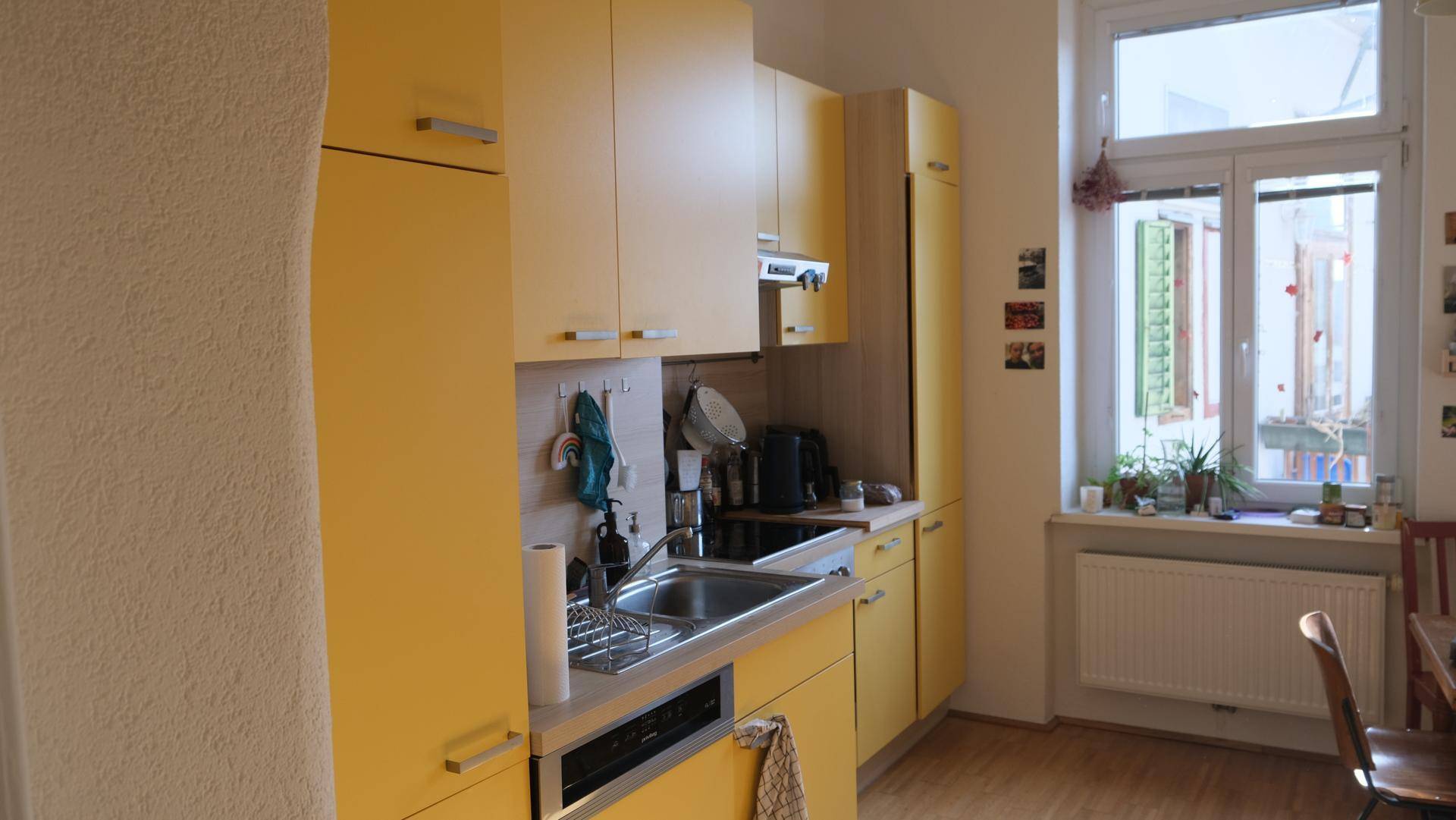 Gelbe Einbauküche mit Spülbecken und Fenster, die viel Tageslicht hereinlässt.