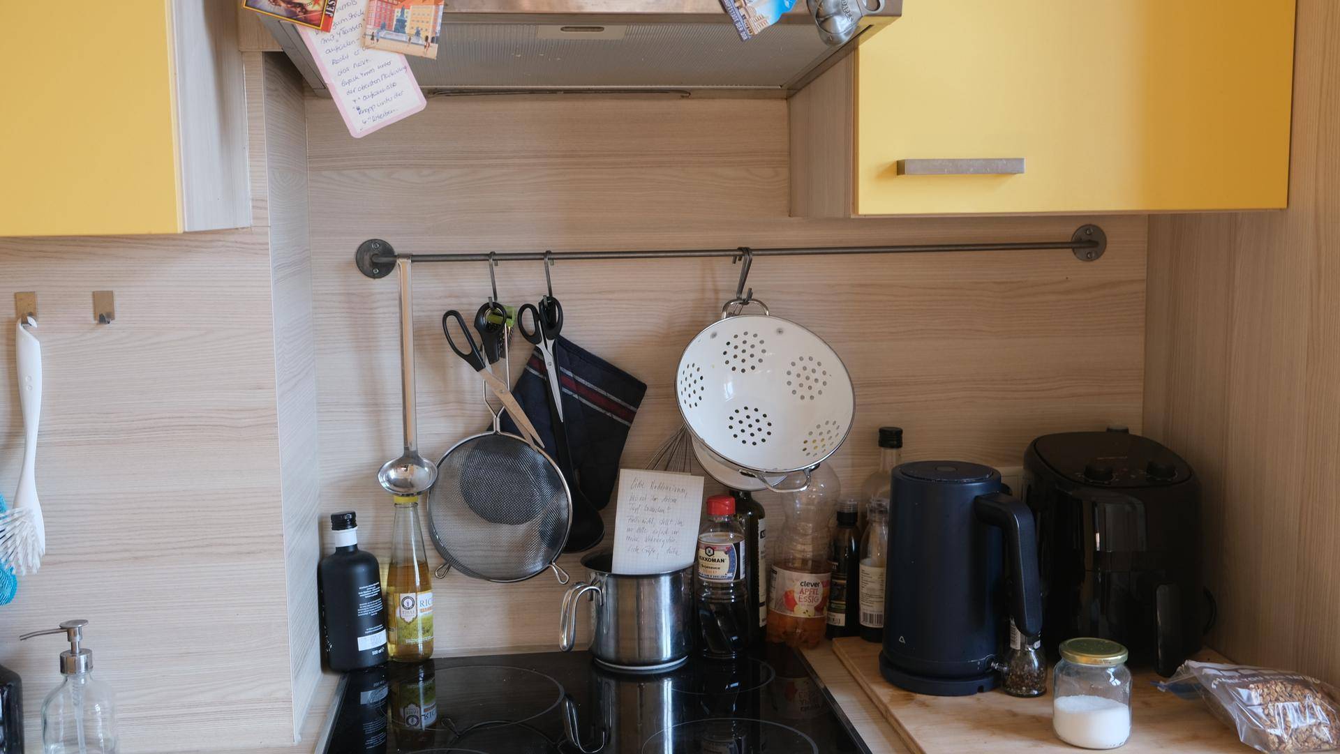Detailansicht des Kochbereichs mit Induktionskochfeld und Küchenutensilien an der Wand.