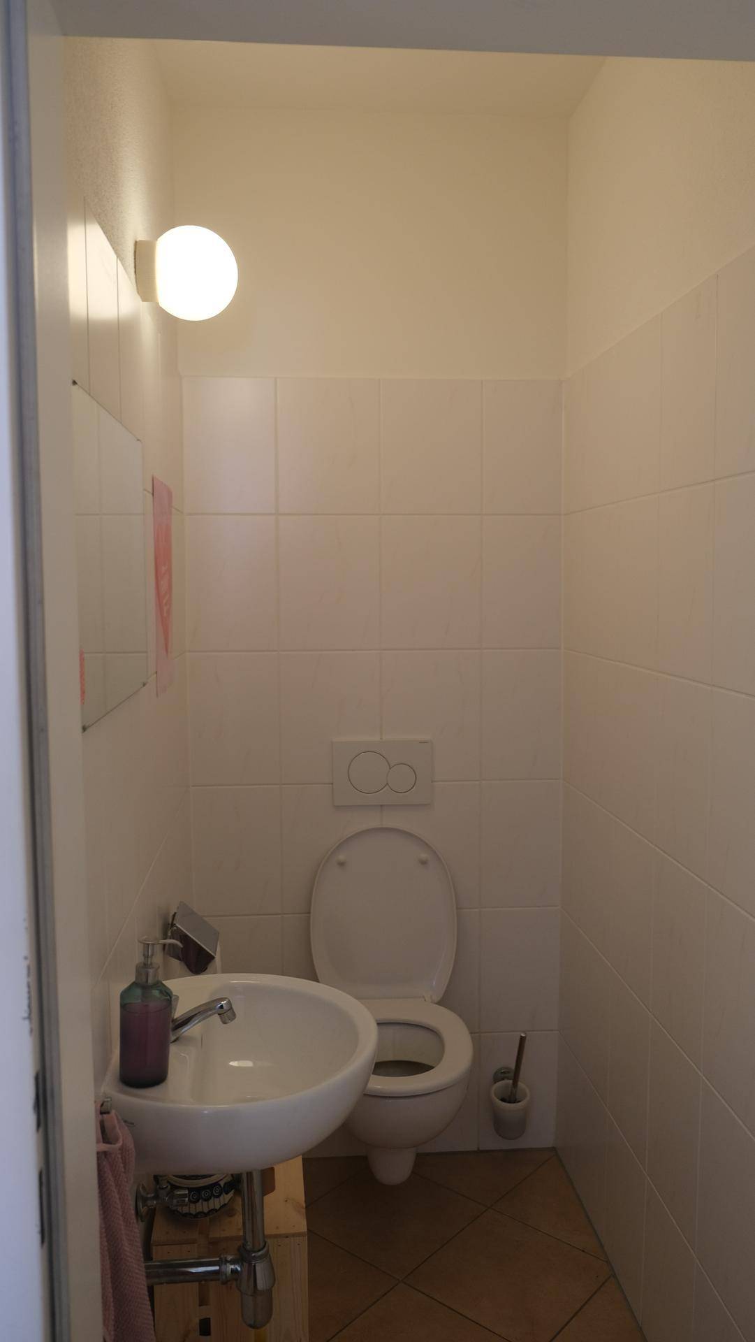 Kleines Gäste-WC mit weiß gefliesten Wänden und einem wandmontierten WC.