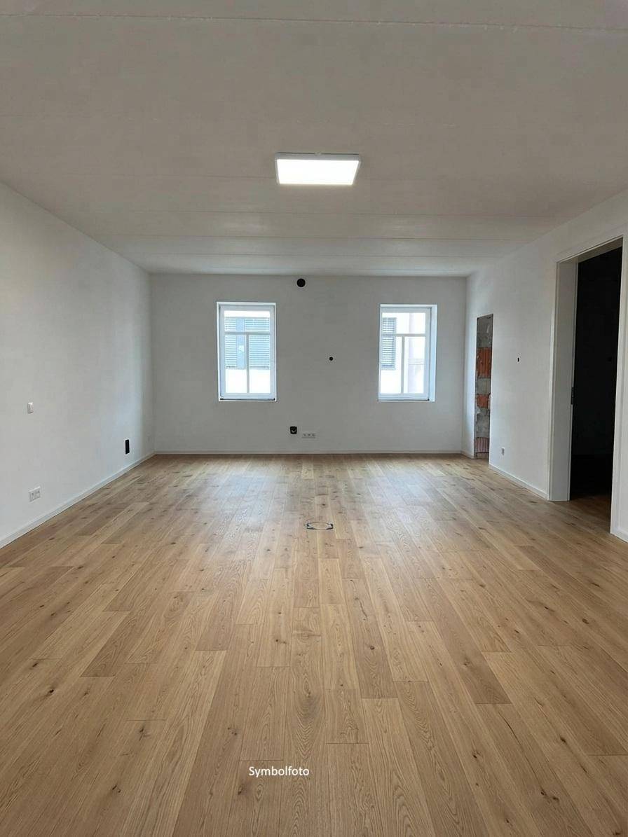 Fertiggestellter Raum mit hellem Holzfußboden, weißen Wänden und Deckenleuchte.