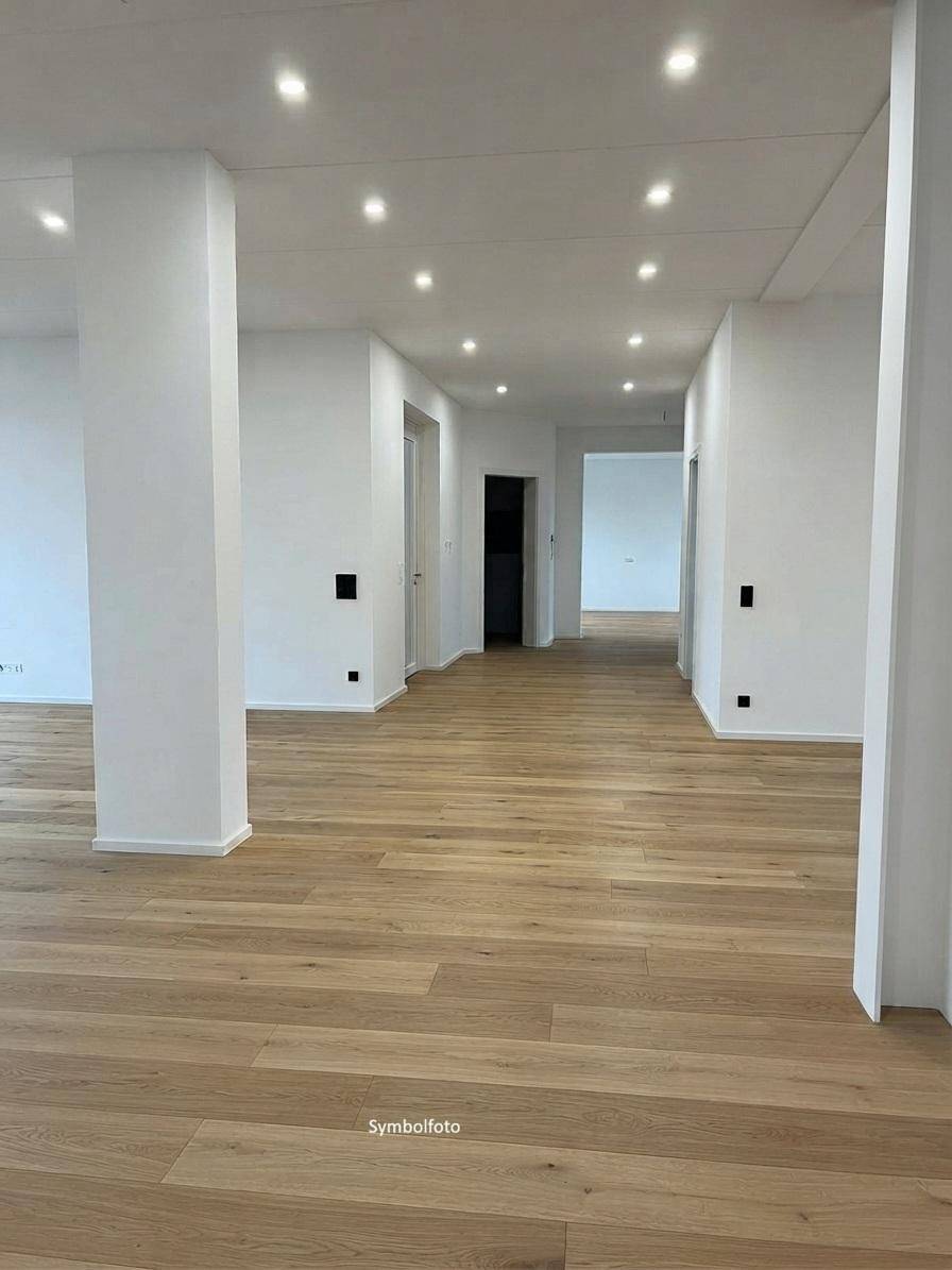 Fertiggestellter, heller Flur mit Holzfußboden, weißen Wänden und moderner Deckenbeleuchtung.
