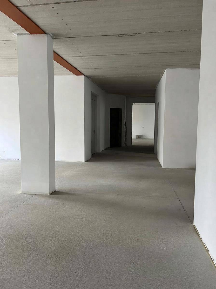 Geräumiger, unfertiger Innenraum mit Betonboden und Säulen, bereit für den Innenausbau.