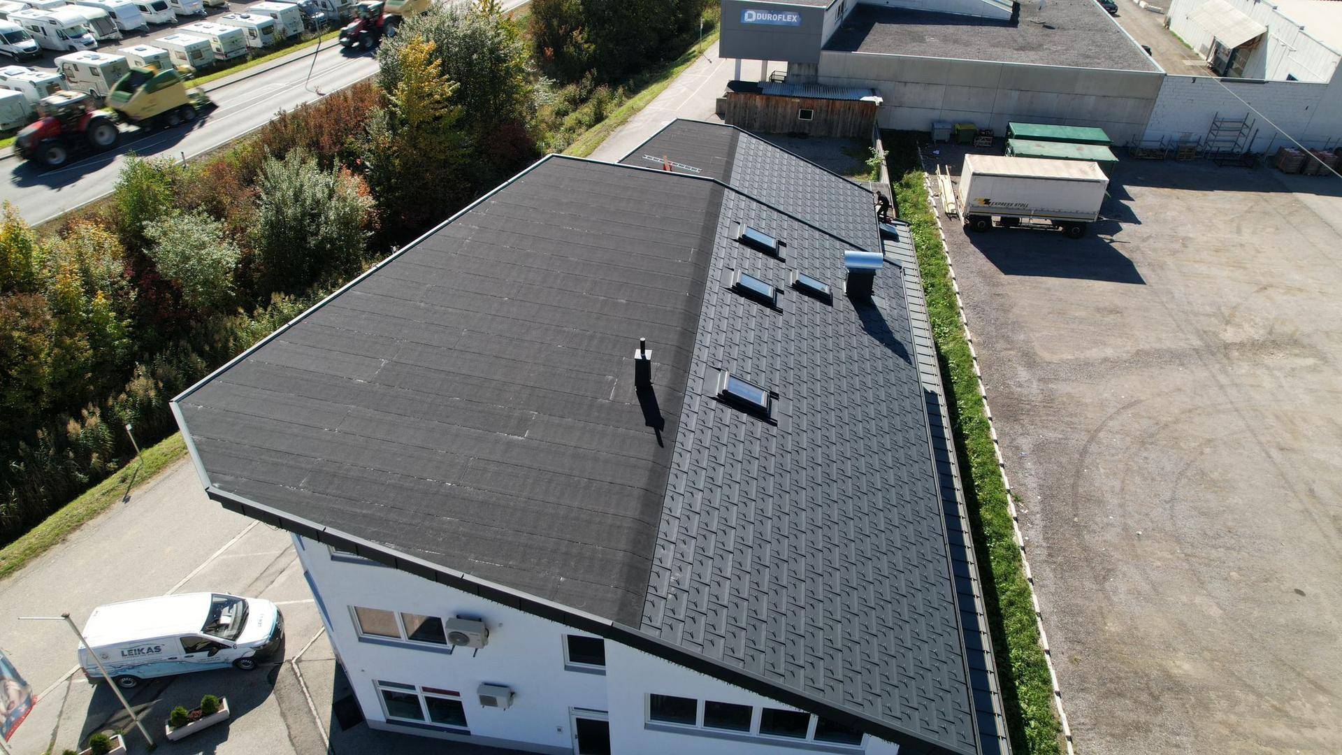 Detaillierte Luftaufnahme des Daches eines modernen Bürogebäudes mit Dachfenstern und Lüftungsanlagen.