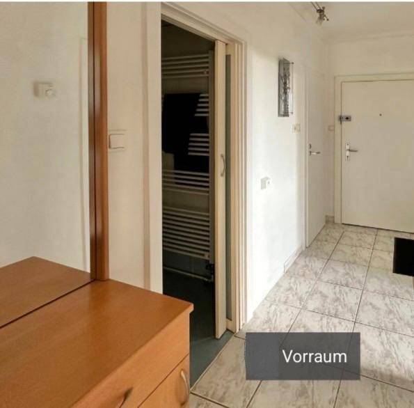 Heller Flur mit Fliesenboden, einem Spiegel und Zugang zu weiteren Räumen der Wohnung.