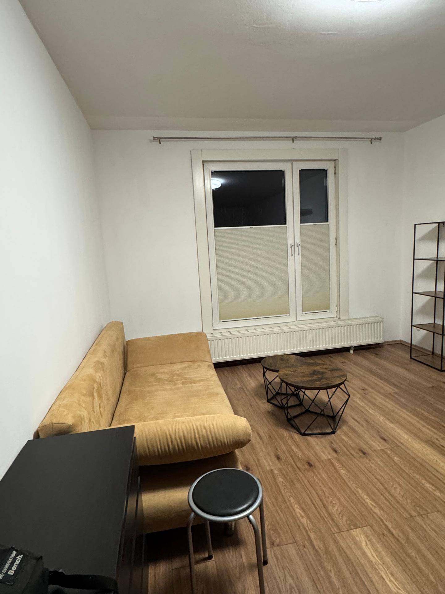 Gemütliches Wohnzimmer mit einem beigen Sofa, modernen Couchtischen und Laminatboden.