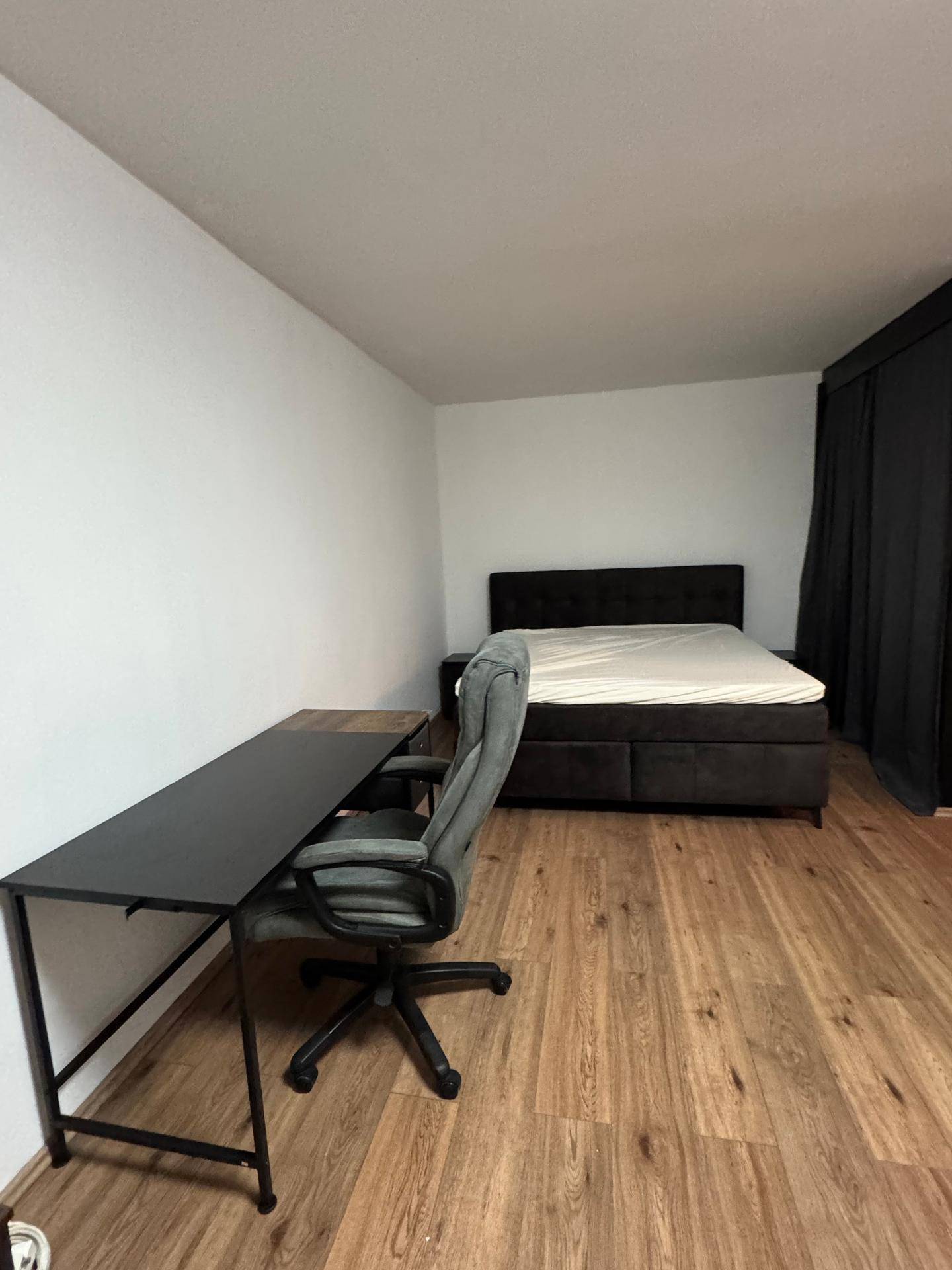 Schlafzimmer mit einem Schreibtisch, einem Bürostuhl und einem Doppelbett.