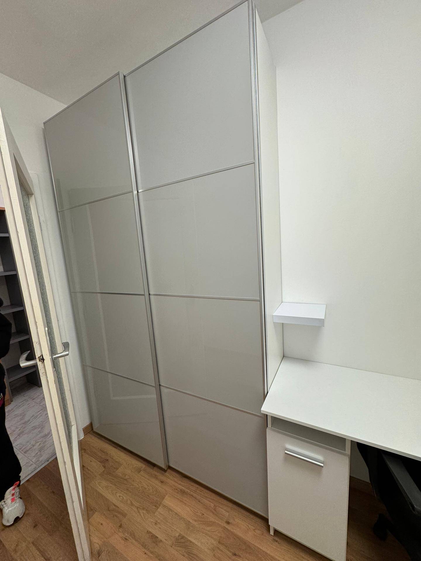 Schlafzimmer mit einem großen Kleiderschrank, einem Schreibtisch und Laminatboden.