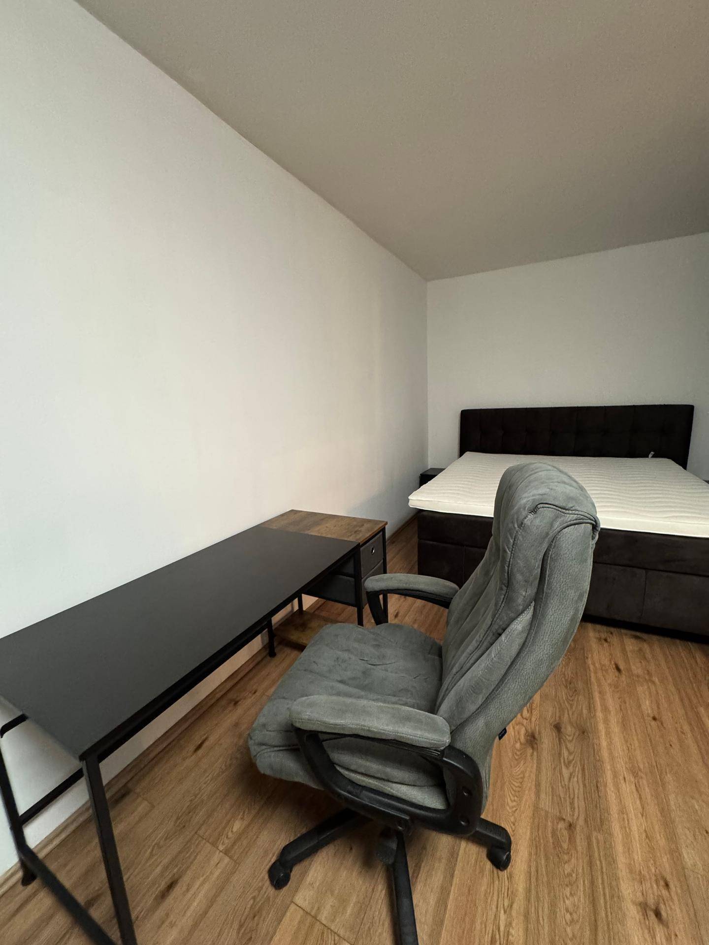 Schlafzimmer mit einem Schreibtisch, einem Bürostuhl und einem Doppelbett.