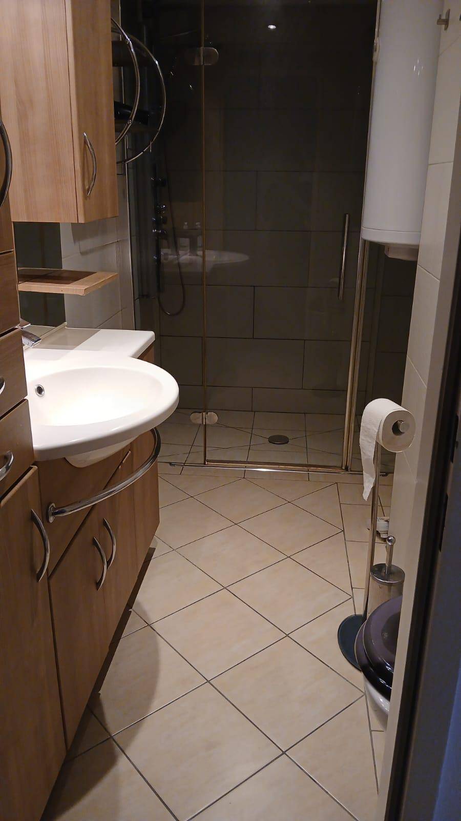 Badezimmer mit Waschbecken, Toilette und einer geräumigen Duschkabine, alles gefliest.
