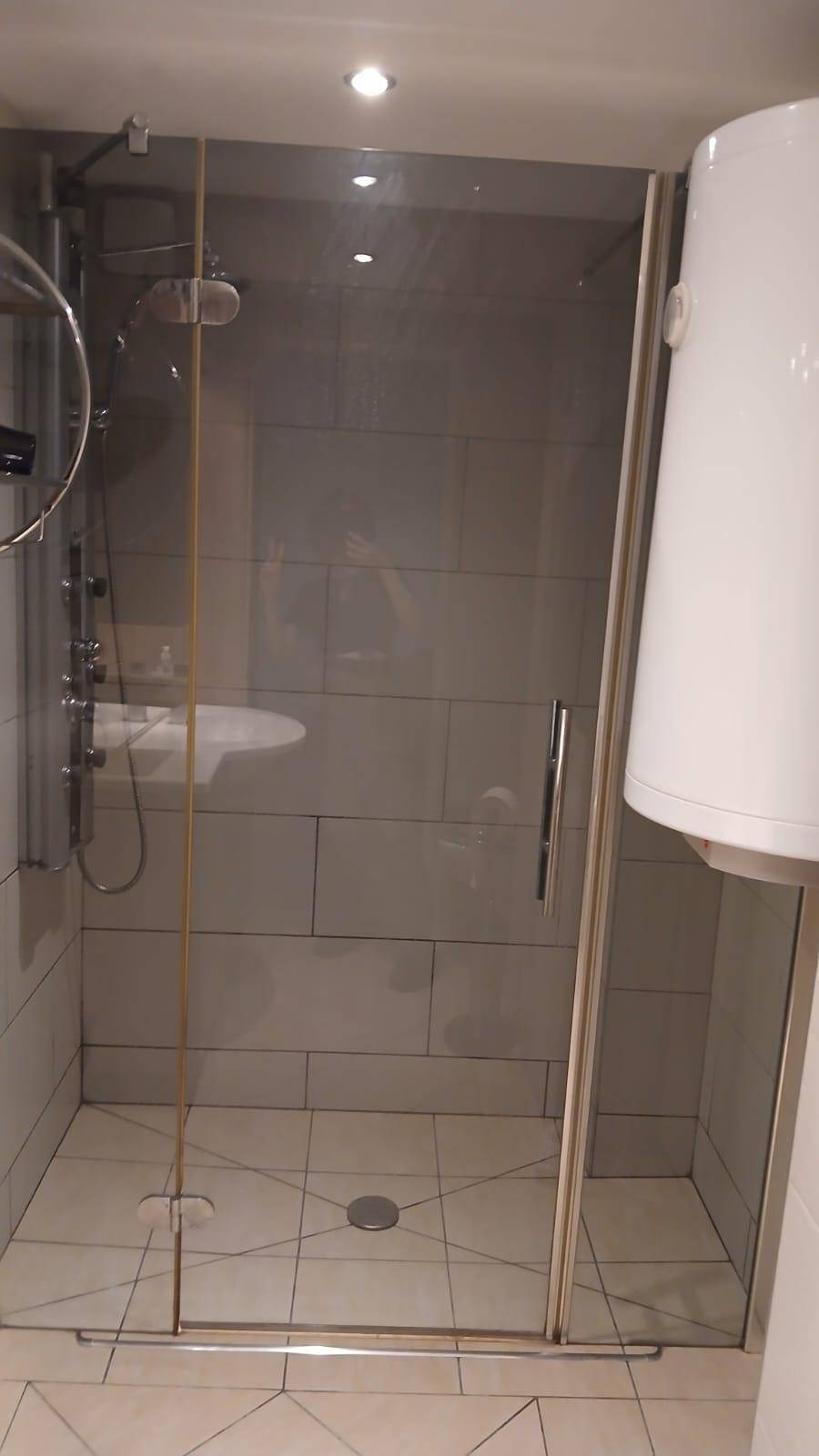Moderne Duschkabine mit Glaswänden und hellen Fliesen im Badezimmer.