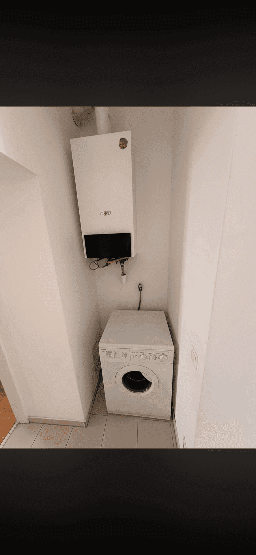 Praktischer Hauswirtschaftsraum mit Waschmaschine und wandmontiertem Heizkessel.