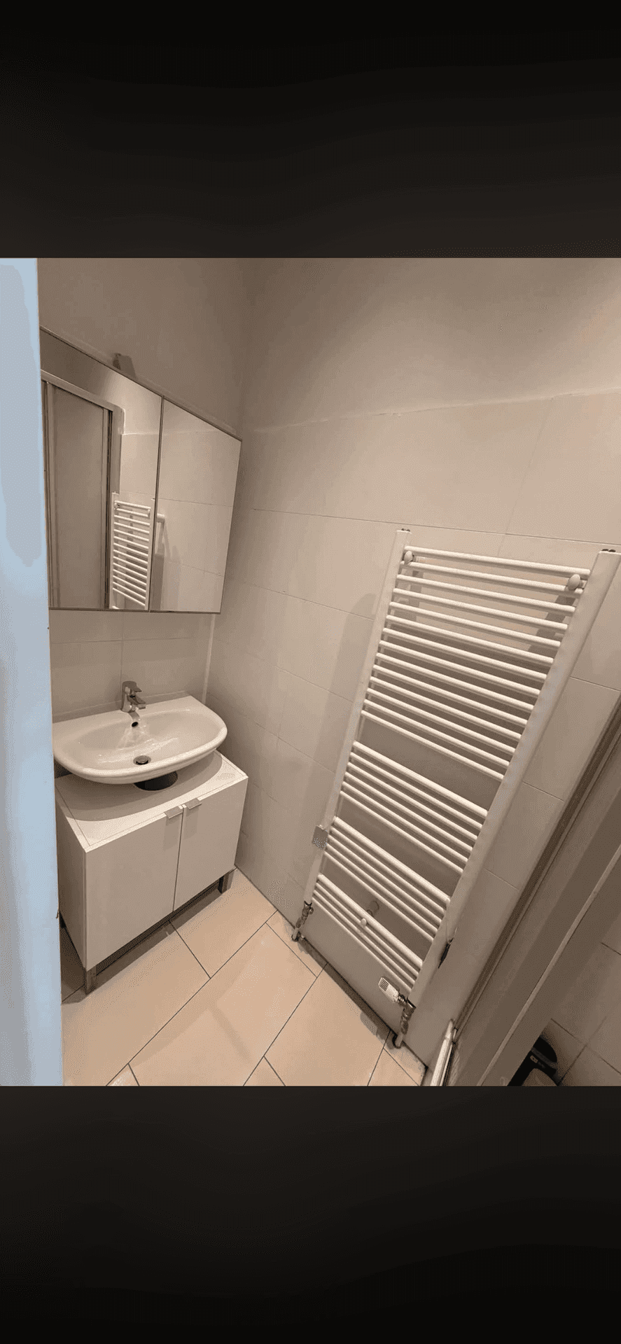 Modernes Badezimmer mit Waschbecken, Spiegelschrank und beheiztem Handtuchhalter.