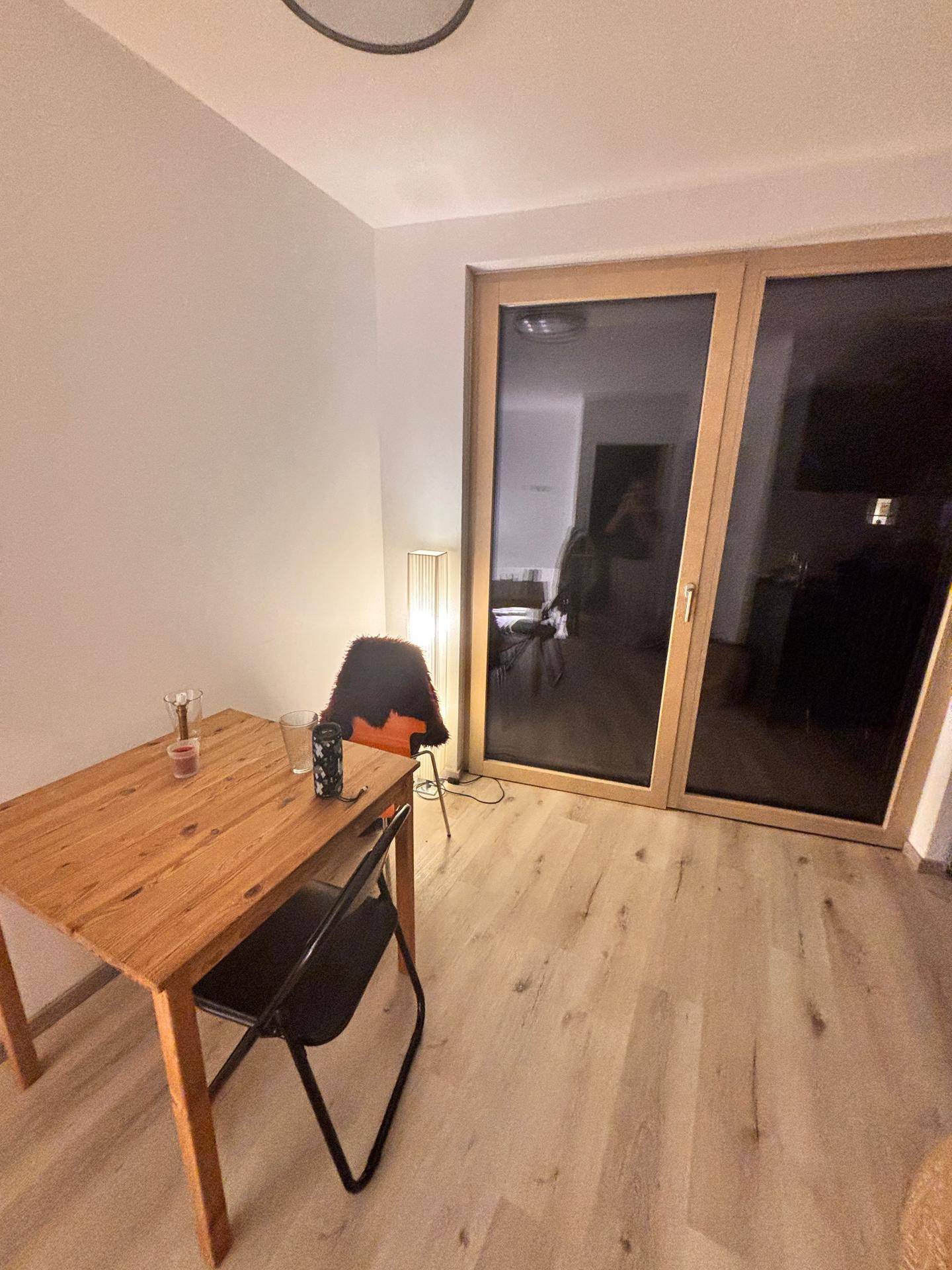 Essbereich mit Holztisch und Zugang zu einem Außenbereich durch große Glastüren.