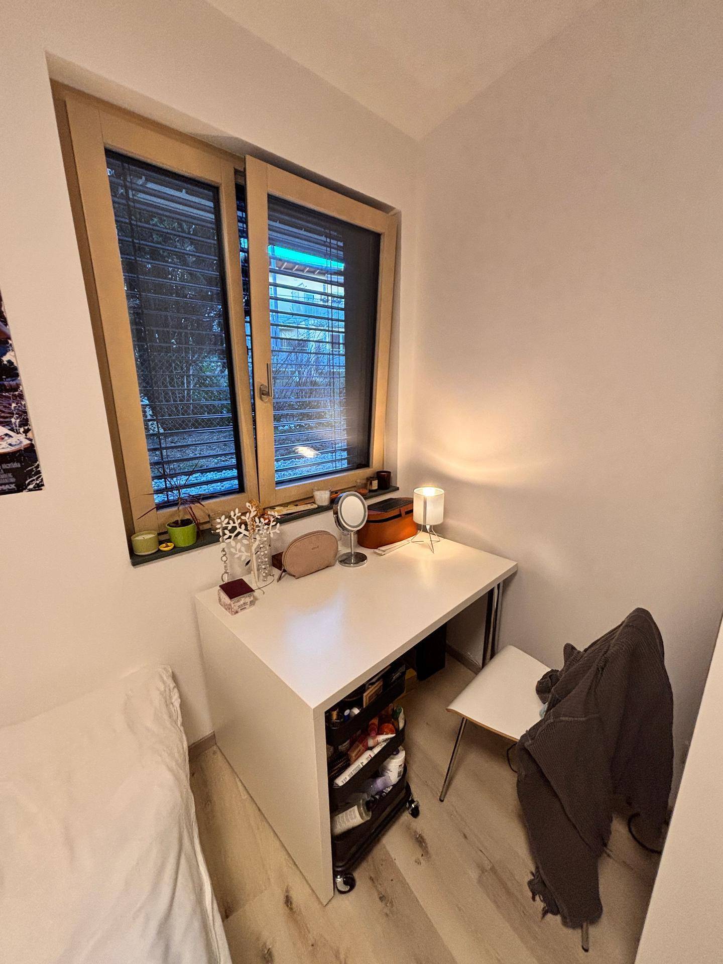 Arbeitsbereich im Schlafzimmer mit Schreibtisch, Fenster und natürlichem Lichteinfall.