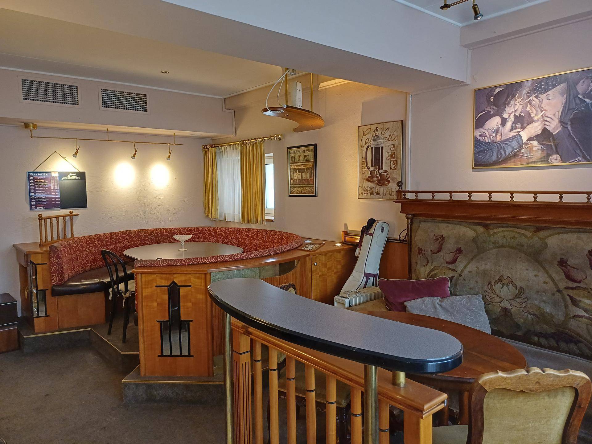 Innenansicht eines Cafés mit erhöhter Sitzecke, kunstvollen Holzdetails und traditioneller Einrichtung, mit Wandkunst.